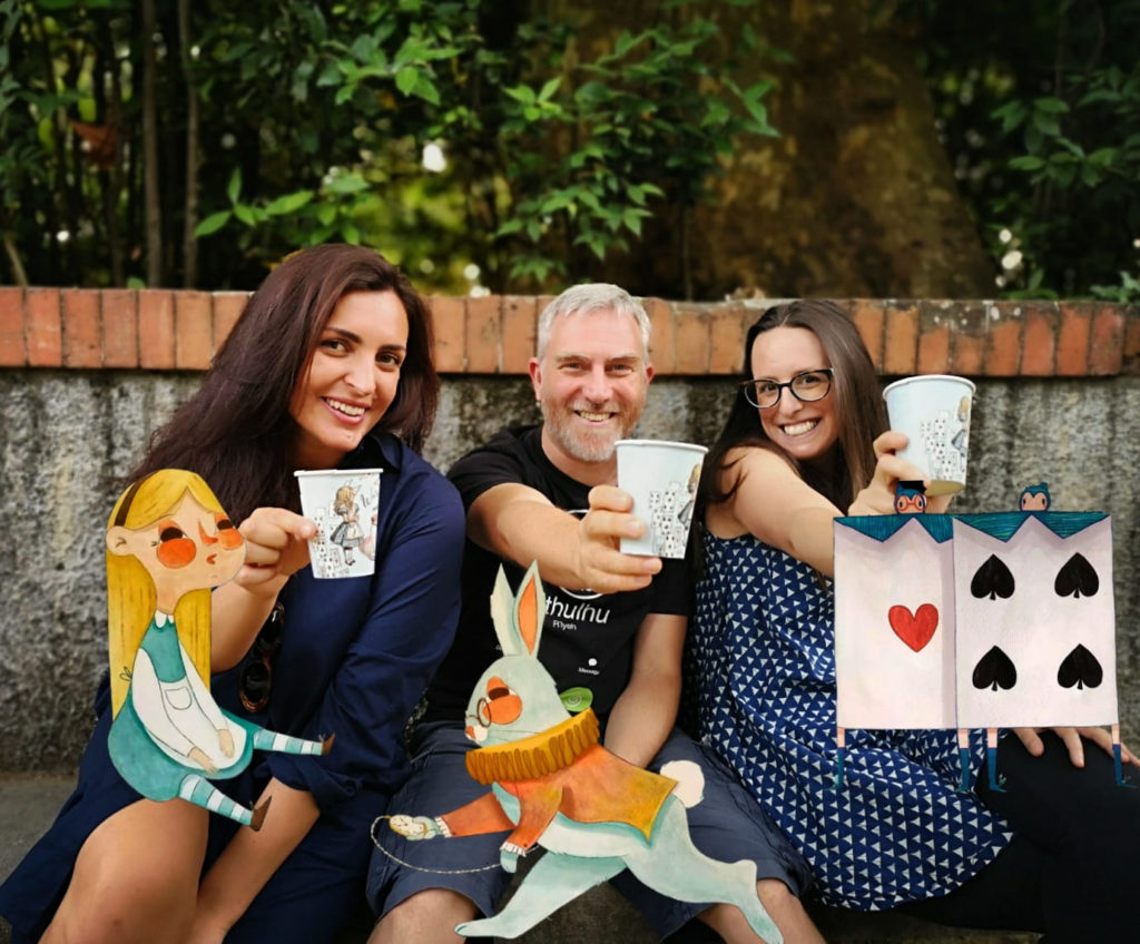 Tre soci di VivaVoce sorridenti con le sagome di Alice, del Bianconiglio e di una carta da gioco del progetto A.L.I.C.E.
