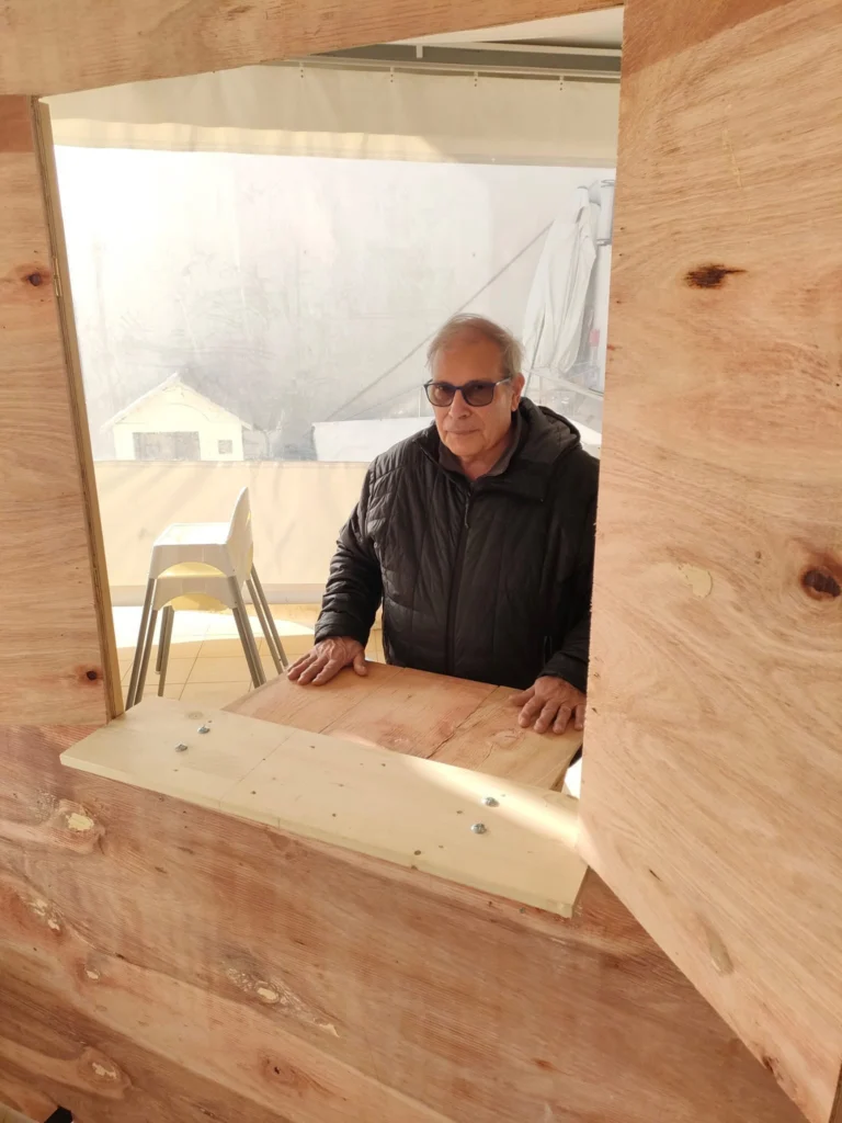 Uno degli scenografi accanto alla struttura in legno con la finestra