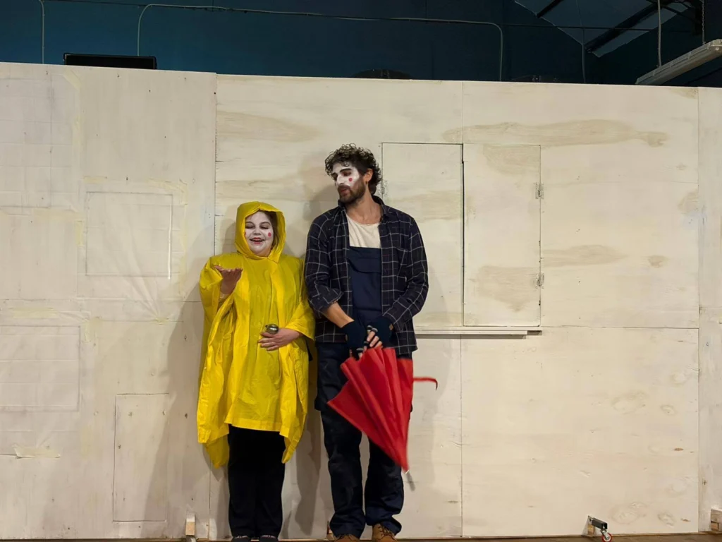 I due interpreti in scena, lei con l'impermeabile giallo e lui con l'ombrello rosso