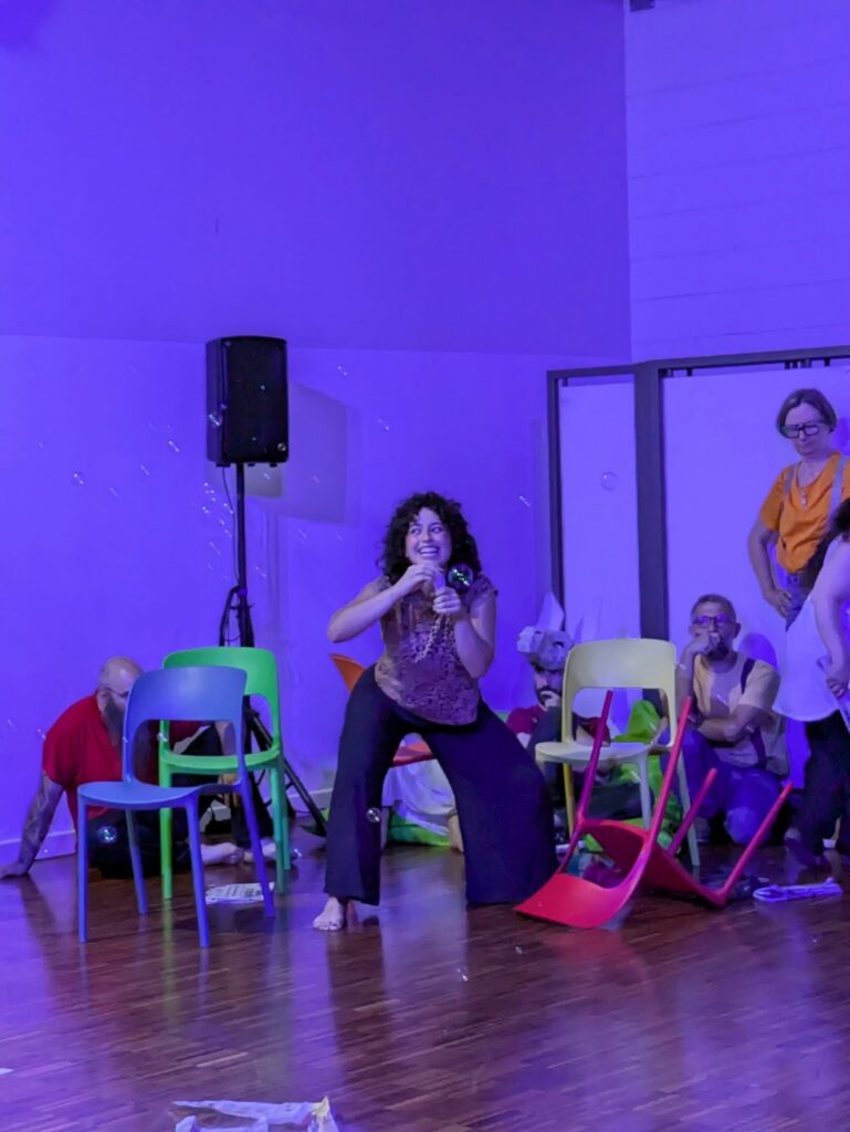 Una scena in luce blu con gli interpreti tra le sedie